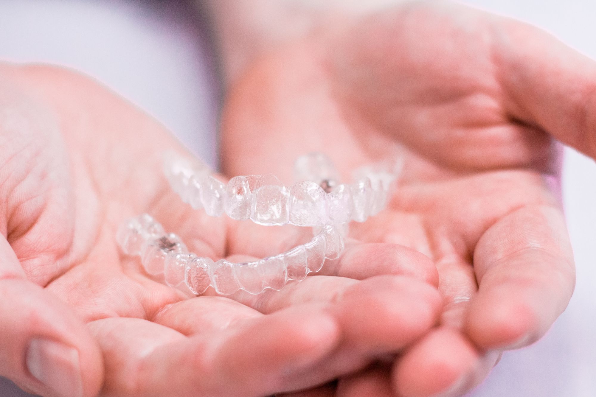 Clear aligners held in hands, showcasing a modern orthodontic treatment option from a Pittsburgh orthodontist, emphasizing discreet teeth straightening solutions in orthodontics.
